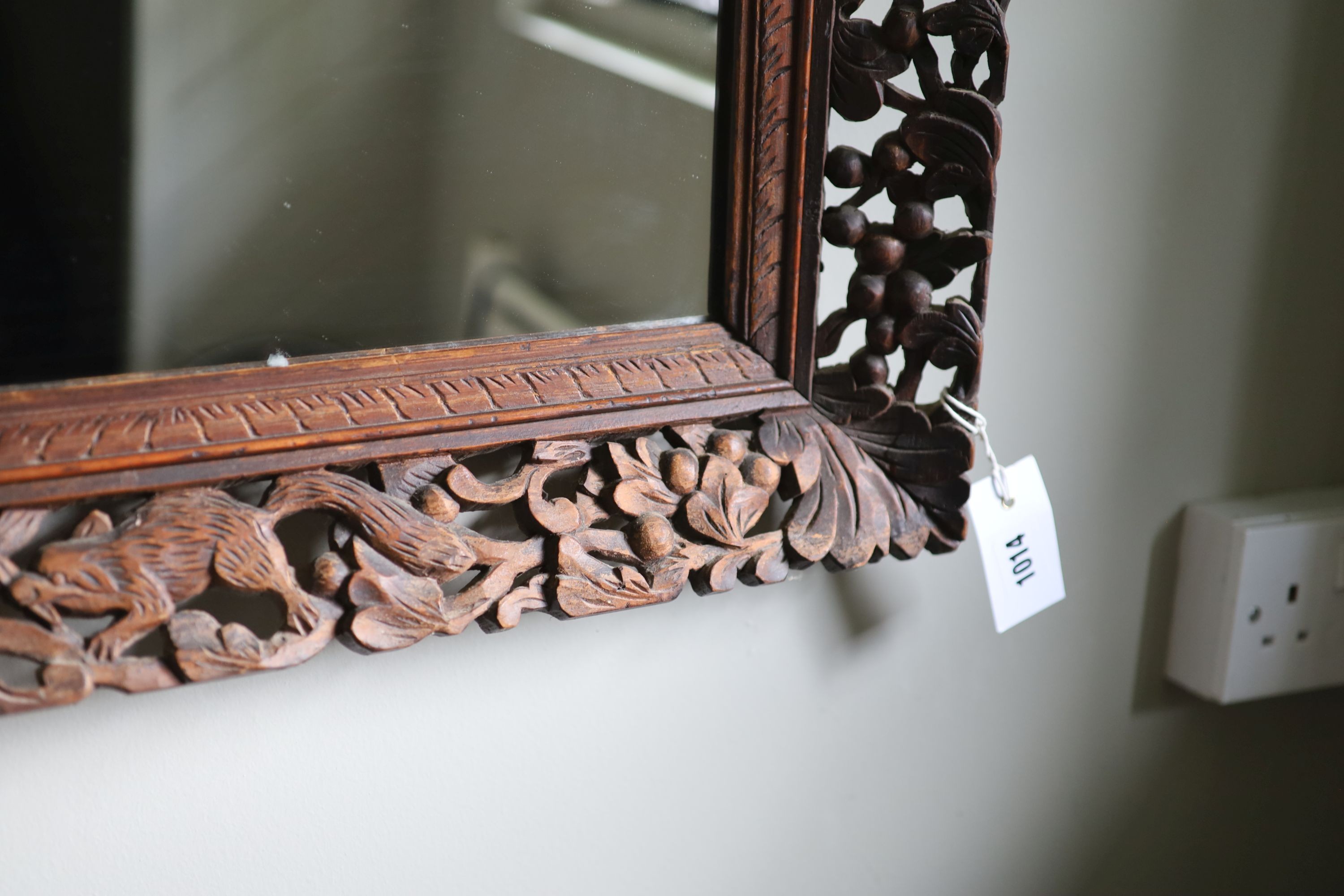 A Continental hardwood wall mirror, carved and pierced with squirrels and fruit, width 77cm height 63cm